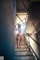 A naked woman standing on a set of stairs.