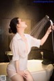 A woman in a white shirt is taking a shower.