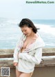 A woman in a white hoodie standing on a pier by the ocean.