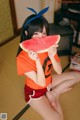 A woman sitting on the floor eating a slice of watermelon.