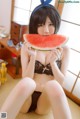 A woman sitting on the floor eating a slice of watermelon.