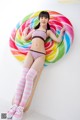 A woman in a bikini laying on a giant lollipop.