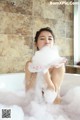 A woman sitting in a bathtub covered in foam.