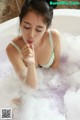 A woman in a bathtub with foam on her face.