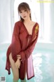 A woman in a red robe standing in a pool.