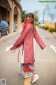 A woman wearing a red scarf walking down the street.