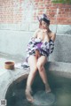 A woman in a kimono sitting on a ledge next to a bowl of water.