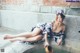 A woman in a kimono sitting on the edge of a fountain.