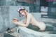 A naked woman sitting in a bathtub holding a bowl.