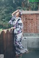 A woman in a kimono standing on a wooden fence.