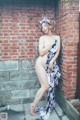 A naked woman standing in front of a brick wall.