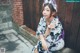 A woman in a kimono sitting on the ground with a cat ears headband.