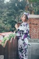 A woman in a kimono standing on a wooden fence.