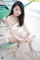 A woman in a white bikini sitting on a beach.