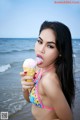 A woman in a bikini eating an ice cream cone.