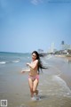 A woman in a bikini running into the ocean.