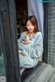 A woman sitting in a window holding a cat.