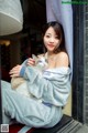 A woman sitting on a window sill holding a cat.