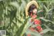 A woman in a straw hat standing in a field of corn.