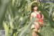 A woman in a red bikini and straw hat standing in a corn field.