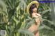 A naked woman in a straw hat standing in a field of corn.