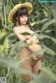 A naked woman in a straw hat holding a pumpkin.