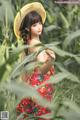 A woman in a red dress and a straw hat standing in a field.