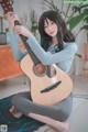 A woman sitting on the floor holding a guitar.