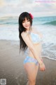 A woman in a blue bikini standing on a beach.