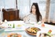 A woman sitting at a table with a plate of food.