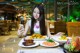 A woman sitting at a table with plates of food.