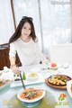 A woman sitting at a table with plates of food.