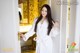 A woman in a white robe standing in front of a door.