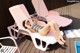 A woman laying on a pink lounge chair next to a pool.