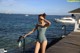 A woman in a bathing suit standing on a dock by the water.