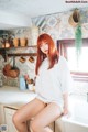 A woman sitting on a kitchen counter next to a sink.