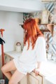 A woman with red hair sitting on a kitchen counter.