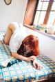 A woman laying on top of a bed next to a window.