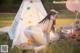 A woman in a bikini sitting in front of a teepee.