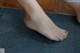 A close up of a woman's bare feet on a tile floor.