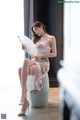 A woman sitting on a stool holding a fan.