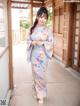 A woman in a blue and pink kimono standing in front of a building.