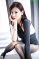 A woman in a black dress sitting on a window sill.