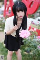 A woman in a black dress holding a pink rose.