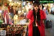 A woman in a red coat and sunglasses at a market.