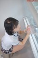 A woman in a school uniform is looking at a refrigerator.