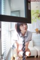 A woman in a school uniform is looking out a window.