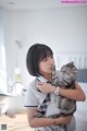 A woman holding a gray cat in her arms.