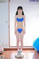 A woman in a blue and orange bikini standing on a scale.