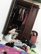 A woman sitting on the floor in front of a closet full of clothes.